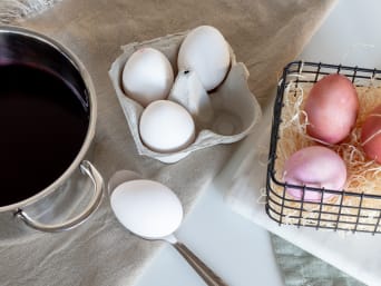 Eier natürlich färben: Weisse Ostereier werden in einen Topf mit Naturfarbe getaucht.