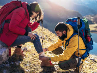 Primo soccorso sport outdoor: un escursionista fascia una caviglia slogata con un kit di pronto soccorso. Primo soccorso sport outdoor: un escursionista fascia una caviglia slogata con un kit di pronto soccorso.