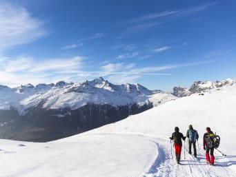 Winterwandern Unterengadin: Gruppe wandert auf schneebedecktem Weg mit Blick auf die Berge.