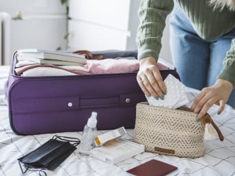 Co można mieć w bagażu podręcznym: kobieta pakuje lekarstwa do kosmetyczki podróżnej.