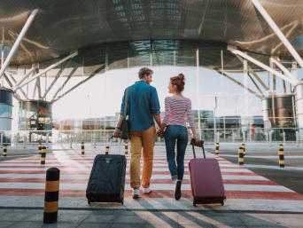A holdall or suitcase: a couple arriving at the airport with their with suitcases.