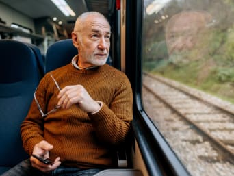 Vacanze per anziani autosufficienti: uomo in pensione viaggia in treno. 