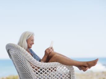 Alleine reisen Tipps – Frau liest auf ihrem E-Book im Urlaub.