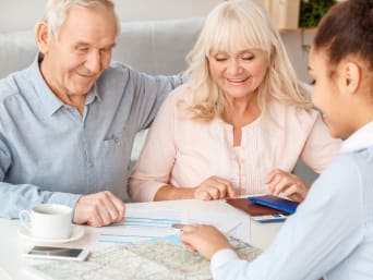 Anziani in vacanza: una coppia si fa consigliare da un’agente di viaggio.