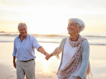 Tipos de viajes para mayores: una pareja mayor pasea por la playa.
