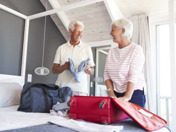 Reise Checkliste – Älteres Paar packt gemeinsam die Koffer.