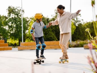 Skateboard für Anfänger: Junge wird von Trainerin im Skateboarding unterrichtet.