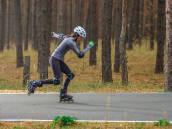 Inline-Speedskating: Eine Frau fährt auf Inlinern und Schutzausrüstung eine Straße entlang.