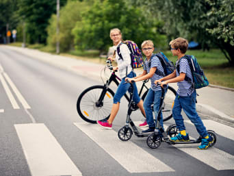 Schulweg mit Velo: Eine Gruppe Kinder fährt mit Tretrollern und mit dem Velo zur Schule.
