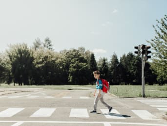 Educación vial infantil: un niño cruza una calle por un paso de peatones.