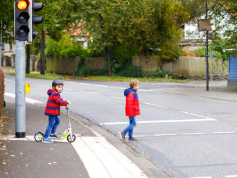 Dzieci w ruchu drogowym: dwójka uczniów przechodzi na drugą stronę ulicy. 