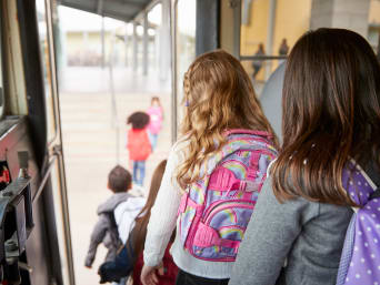 Schulweg mit dem Bus – Schulkinder steigen nacheinander aus dem Bus aus.