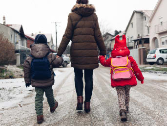 Schulweg zu Fuß – Mutter läuft mit den Kindern zur Schule