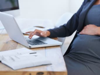 Werken zwangerschap: Zwangere vrouw werkt thuis op laptop.