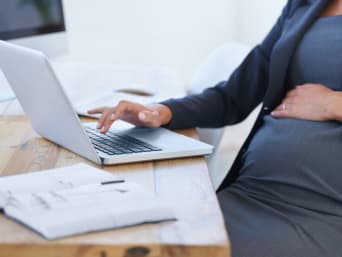 Werken tijdens zwangerschap – Zwangere vrouw werkt thuis op een laptop.