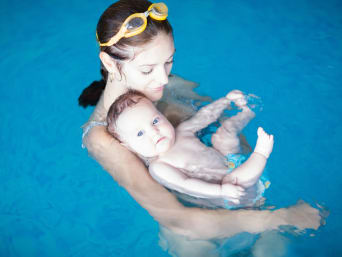 Âge pour apprendre à nager : mère et enfant pataugeant dans la piscine. 