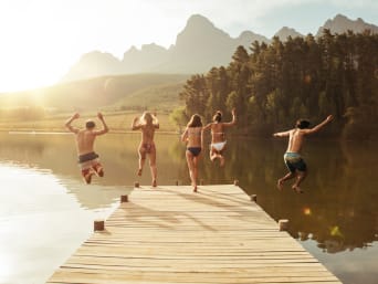 Grupo de bañistas saltando al lago desde un embarcadero