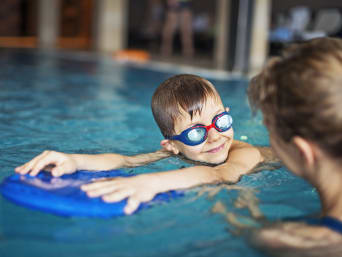 Zalety pływania: chłopiec podczas nauki pływania na pływalni.