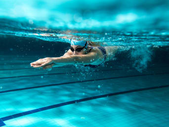 Korzyści z pływania: kobieta zanurzona w wodzie podczas treningu. 