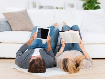 Benefici lettura: una coppia legge un libro cartaceo e su tablet.