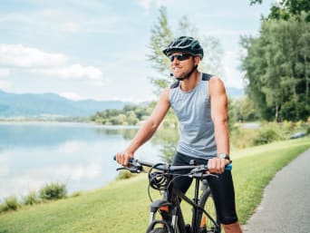 Sporten tegen stress: fietser op een mountainbike fietst langs een meer.