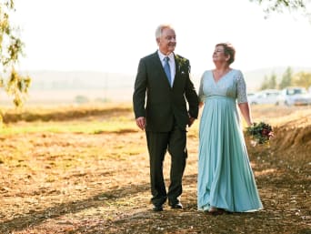 Zilveren huwelijkskledij: ouder echtpaar in feestkledij gaat buiten wandelen.