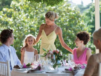 Kleidung für die Silberhochzeit: Hochzeitsgäste sitzen auf der Terrasse am gedeckten Tisch.