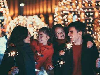 Sylwester z dziećmi: rodzina świętuje nowy rok obserwując zimne ognie. 