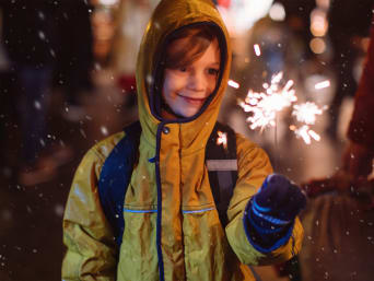 Oudejaarsavond met kinderen ideeën: jongen kijkt naar een vuurwerksterretje.