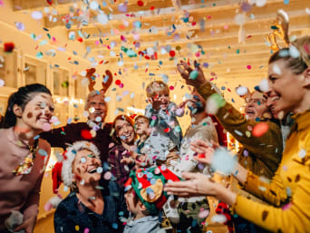 Things to do New Year’s Eve with kids: A family celebrates New Year’s Eve together by throwing confetti.