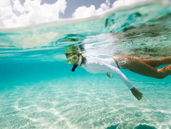 Zonbescherming in het water: vrouw draagt UV-werend shirt tijdens het snorkelen.