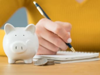 Oszczędzanie pieniędzy – kobieta zapisuje swoje wydatki w planerze budżetowym.