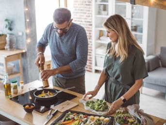 Consumo sostenibile – Una coppia prepara una ricetta vegetariana con verdure di stagione.