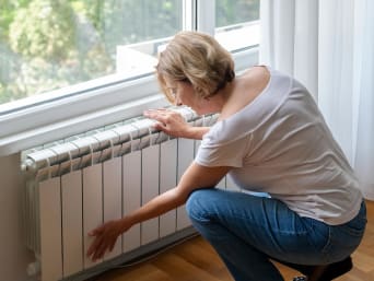 Risparmiare sul riscaldamento – Una donna controlla se il termosifone deve essere spurgato.