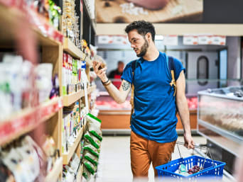 Faire ses courses pas chères : un homme compare les prix au supermarché.
