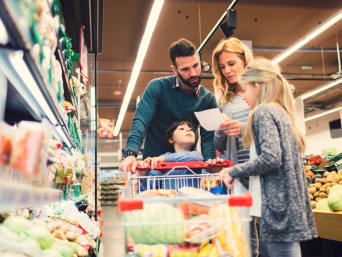Cómo ahorrar en la cesta de la compra: una familia consulta la lista de la compra en el supermercado.