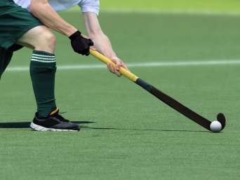 Wat is hockey? - Man speelt de bal met zijn hockeystick.