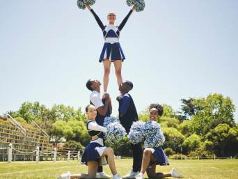Cheerleading: Eine Gruppe von Cheerleadern cheert auf dem Rasen.