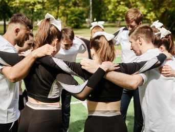Cheerleading-Ausrüstung: Ein Cheerleading-Team steht in einem Kreis und bespricht sich.