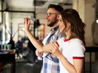 Dart für Anfänger – Mann und Frau spielen eine Runde Dart gegeneinander.