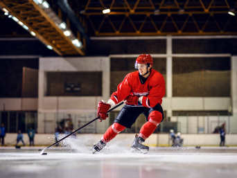 Eishockey spielen: Ein Eishockey-Spieler führt den Puck mit dem Schläger gekonnt über die Eisfläche. 