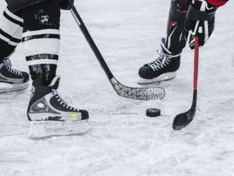 Eishockey für Anfänger: Momentaufnahme im Hockeyspiel, in der zwei Spieler um den Puck kämpfen.
