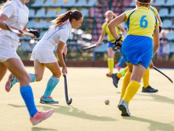 Feldhockey Regeln: Zwei Damenmannschaften spielen Feldhockey gegeneinander.