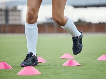 Feldhockey Training: Eine Spielerin trainiert ihre Koordination mit einem Hütchenspiel.