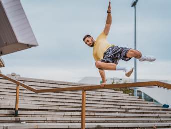 Parkour für Anfänger: Traceur führt einen Vault über ein Geländer aus. Parkour für Anfänger: Traceur führt einen Vault über ein Geländer aus.