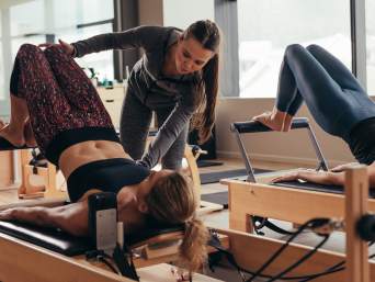 Was ist Pilates – Trainerin korrigiert bei einer Übung. 