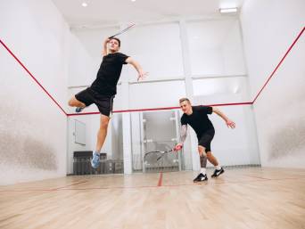 Squash Sport: Zwei Athleten spielen gemeinsam Squash auf einem Squashcourt.