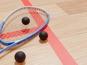 Squash Ausrüstung: Ein Squashschläger und Squashbälle liegen auf dem Court.