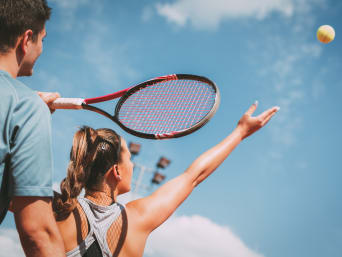 Tennis leren – Vrouw oefent haar opslag.