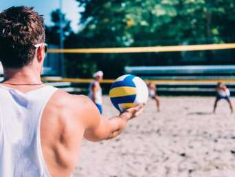 Volleyball Anfänger: Spieler macht einen Aufschlag beim Beachvolleyball.